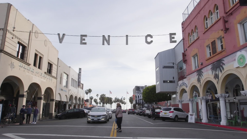 Los Angeles , California / United States - 04 12 2019: A gimbal shot passing underneath the Venice Beach Sign in Los Angeles California while slowly tilting up. The shot is in slow motion on an overcast day