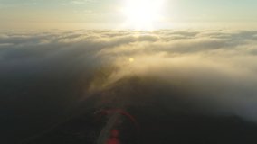 Amazing golden clouds moving softly on the sky and the sun shining through the golden fog with beautiful rays and lens flare. 4K Drone flying slowly through heavenly beautiful golden cloudscape