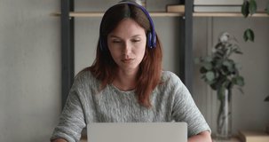 Serious woman in headphones talk using laptop and video conference app having conversation with colleague distantly due self-isolation corona virus quarantine. Solve issues, working remotely concept