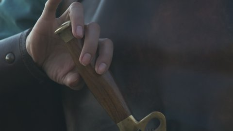 Warrior woman's hand takes a sword out of the sheath, close-up
