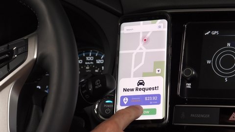 Car driver for a ride sharing service using his mobile phone to receive new requests from clients. Smartphone app notifying the vehicle driver.