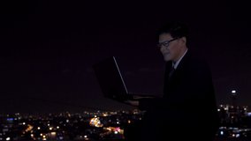 Young Asian businessman using laptop computer with internet video conference meeting with business teamwork brainstorming ideas for success project at office building with city night lights background