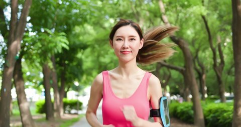sport asia woman running with smartphone in the park
