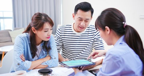 Young asian couple looking house with real estate agent by tablet pc