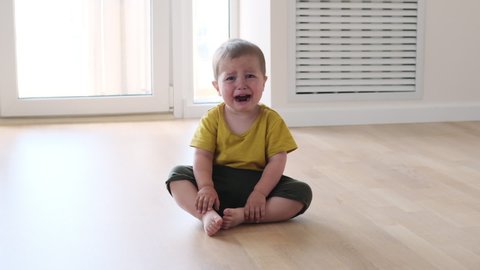 Little baby boy crying while sitting at floor