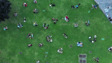 Couples in love and other people rest on the green lawn at the end of the day - the end of the quarantine. Ending social distancing in Kyiv. Aerial View.