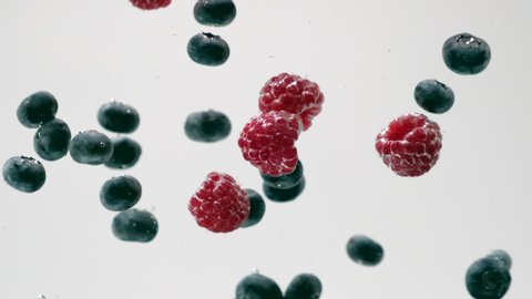 Berry. Raspberry, blueberry and mulberry falling into transparent water on black white background. Mix of sweet fresh berries and fruits splashing in aquarium, underwater. Healthy organic food