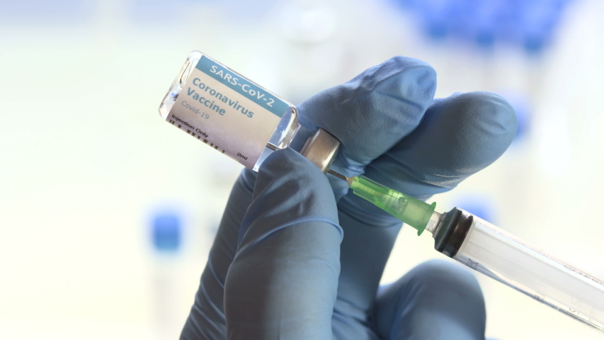 Doctor draws coronavirus vaccine into a syringe. The holy grail that will save the world is a working vaccine for coronavirus like this one in a glass vial being picked up by a gloved hand in a lab Royalty-Free Stock Footage #1056453593