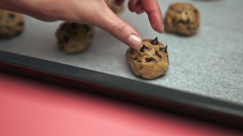 Close-up Female hands adding Chocolate Chips on top of Chocolate Chip Cookies raw dough bowls in 4K. 