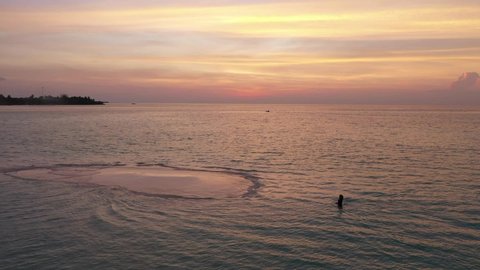 Aerial view of beach with a woman walking at sunset