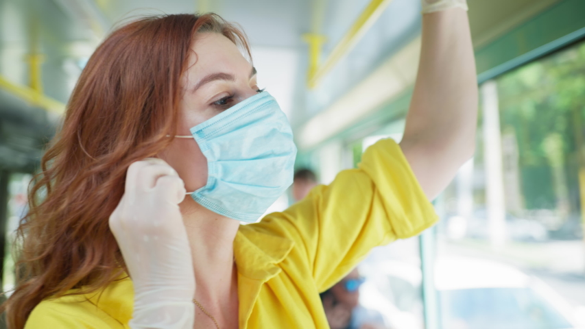 pandemic, smiling happy girl wearing gloves rides public transport after release of quarantine and takes off her medical mask while enjoying bus ride after being isolated from virus and infection Royalty-Free Stock Footage #1056466325