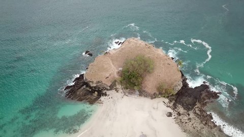 A top-down drone shot of an idyllic Koka Beach. Hidden gem of Flores, Indonesia. Headland going straight into the open sea. Beauty in the nature. Calm waves washing the cliff's slopes. Serenity. 
