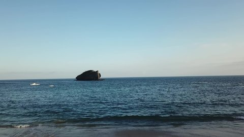 A panoramic view on idyllic Koka Beach. Hidden gem of Flores, Indonesia. Beach is gently washed by waves. Steep hills going straight into the sea. Soft colors of sunset. Serenity and calmness
