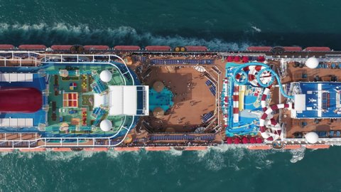 Carnival Cruise liner sailing to Caribbean Islands, Miami, 2019. Stunning 4K aerial view of beautiful white passenger ship with passengers relaxing on upper deck with waterslides and sport playgrounds