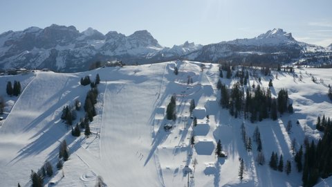 Dolomites in winter aerial shoot over a perfect snowpark in Italy, ski resort in the morning sunrise.
