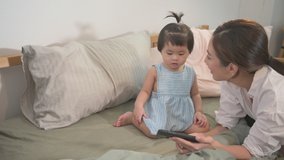 An Asian mother and her daughter are playing together in bed, home safely , parenthood , family concept