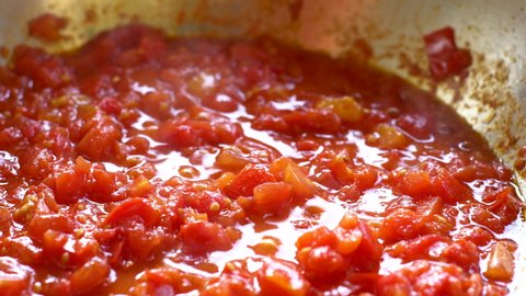 Tomato sauce.  Close up.
Boiling tomato sauce made from chopped fresh ripe tomatoes.
Cook stirs sauce with wooden spatula.
Italian cuisine.