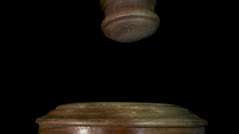 Gavel being struck to decide an auction or guilty verdict in court. Black background. Slow motion.