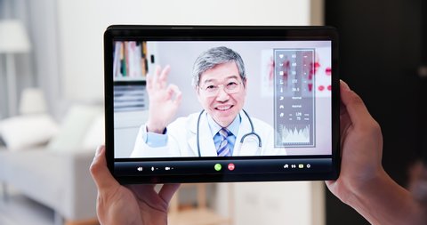 Telemedicine concept - Asian elder doctor is online to have video chat though tablet pc with patient at home