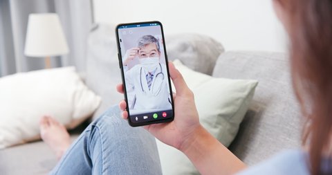 Telemedicine concept - Asian elder male doctor wear face mask and have video chat through cellsphone with patient at home