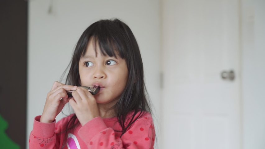 A 4 years old asian little girl is playing harmonica in the morning time, concept of musical education for kid and activity at home for child development.