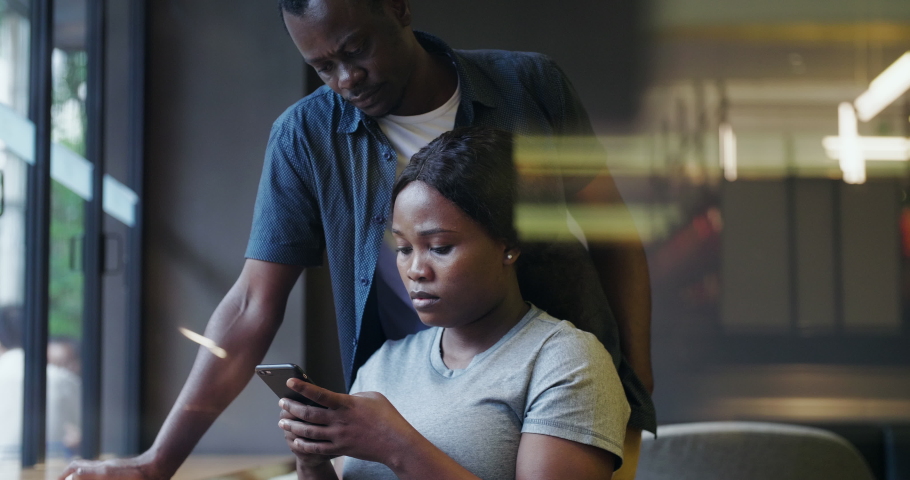 Close up of serious Black couple looking at mobile phone in hand feel worried and depress people trying to solve problem working discussion together in office | Shutterstock HD Video #1056481661