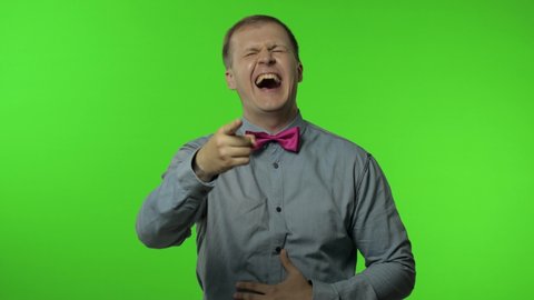 Amused happy man pointing finger at camera and laughing out loud, holding belly with hilarious laughter, making fun of ridiculous appearance, joke. Portrait of guy posing on chroma key background
