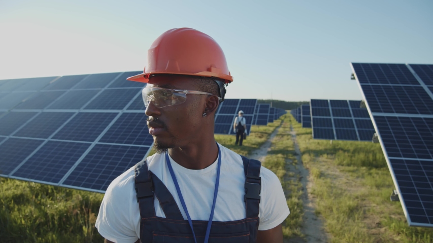 Portrait of afro-american ecology worker in hard hat standing at solar panel field. Industrial people. Sustainable energy. Technology. Royalty-Free Stock Footage #1056485732