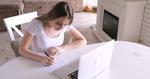 Teenage girl studying online from home with distance teacher. Teen school student distance learning in internet making notes, doing homework, watching video tutorial course concept.
