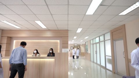 Wide shot of Lobby waiting area in modern hospital or healthcare facilities with patient at information counter and group of professional doctors and nurses working in medical center health services.