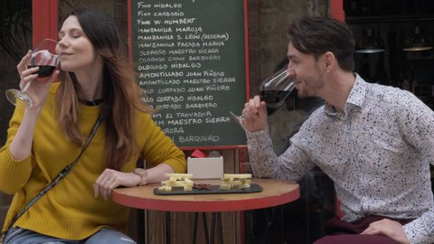 Young loving couple relaxing and drinking red wine with cheese and nuts in street cafe. Enjoyable time together