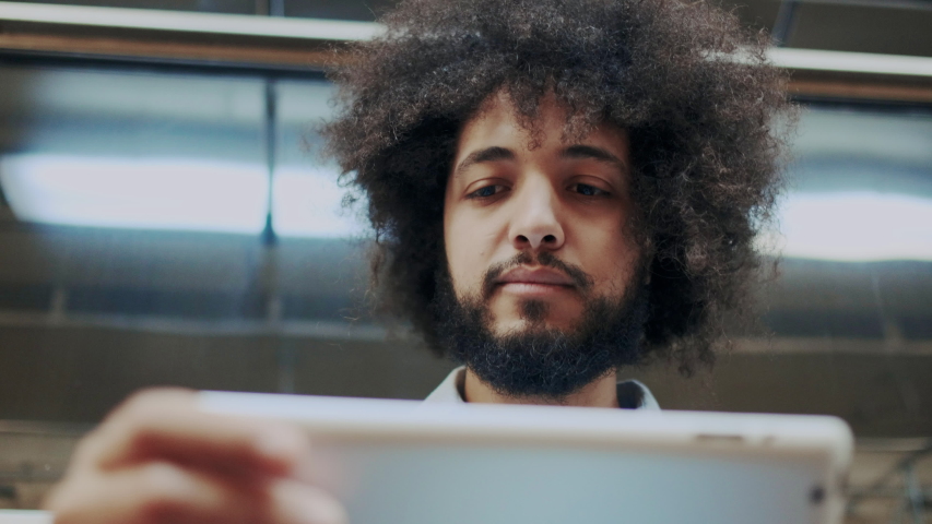 Close-up. Young Curly Handsome Man with Laptop or Tablet PC in Subway. Concept of Modern Remote Business Process, Learning Online, Distance Education, Checking Tutorial. Public Transportation.