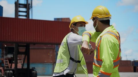 Engineer team and construction worker wear hard hat and mask and greeting bumping elbow in workplace such as container or industry. Protect from COVID-19 coronavirus While working, healthcare concept