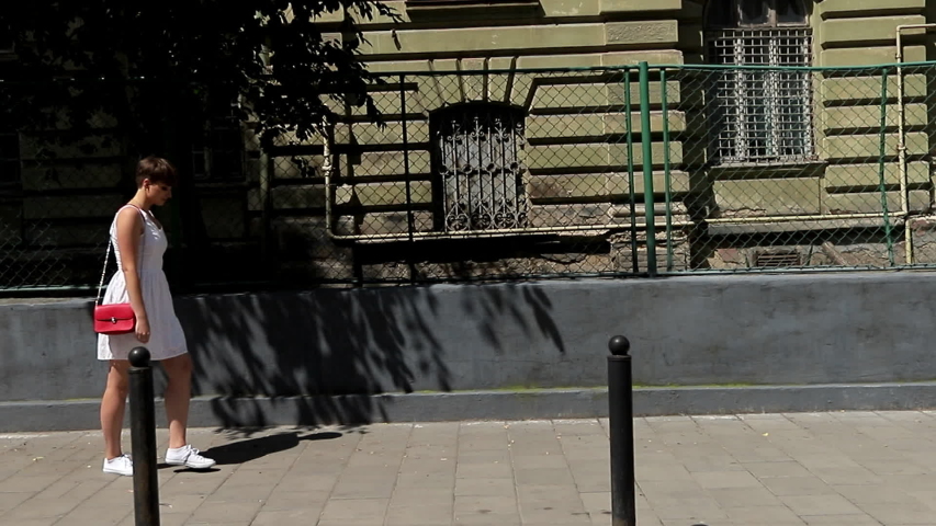 Beautiful woman smiling at camera enjoying urban city lifestyle. Young Funny girl in a white dress walking in the Town and enjoying her Life.