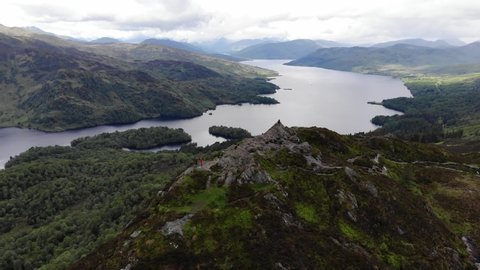 Extended drone shot of Scottish highlands, showing mountains and lakes, as drone circles Ben A'an in the Trossachs
