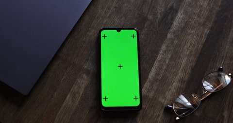 Top view, Smart phone place on table wood with green screen and tracking dots, Close-up the cell phone is on the brown desktop with chroma key, Green screen telephone, slider and top view.