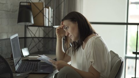 Stressed woman holding papers calculate domestic bills at home worried about bankruptcy 
