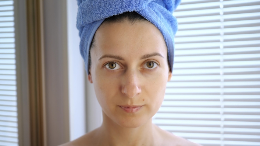 Young woman after bath or shower with a towel on your head used pink collagen hydrogel cosmetic patches under eyes. Lifting of wrinkles. Skin care at home. Cosmetology procedure. | Shutterstock HD Video #1056520880