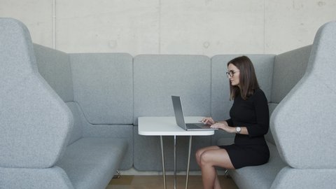 Woman working on laptop in cubicle and social distancing