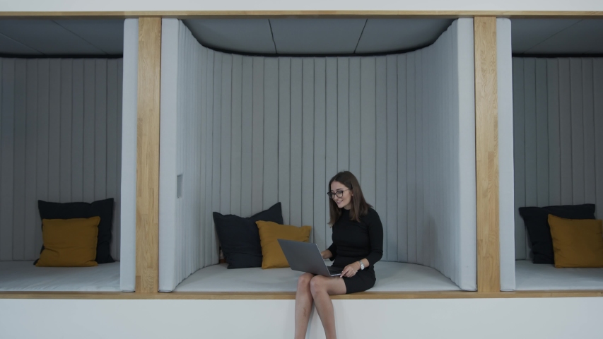 Woman making a video call on laptop in cubicle and social distancing