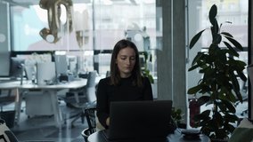 Woman working on laptop in office and social distancing