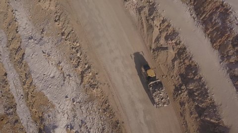 Dump trucks with placer gold in the gold mining quarry. Following shot from above