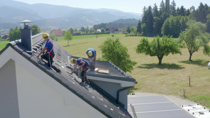 Roofers working on roof of a detached house. Sideways view | Shutterstock HD Video #1056528065