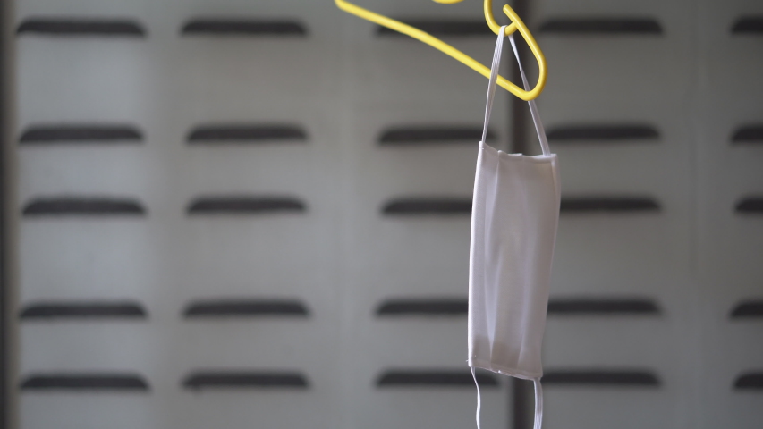 white cloth face mask on clothes hanger for dry after clean wash for close mouth nose to protect covid-19 coronavirus or bacteria and PM 2.5 dust smoke to cough sneeze or flu by air pollution on 4K