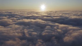 Camera is raising above from the thick fog above the beautiful ocean of clouds at sunrise. Sun is rising above the endless sea of clouds until the horizon. Amazing nature landscape, 4K drone in sky - Powered by Shutterstock - Get 15% off with code: PIKWIZARD15