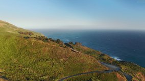 Drone flying above highway at scenic Pacific Ocean coast, California. Clear blue sky above beautiful landscape at sunset. Amazing wild nature landscape in summer. 4K nature and outdoor adventure