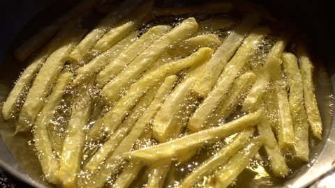 French fries. Finger chips. Close up. 
Frying and stirring potato strips in hot boiling sunflower oil.