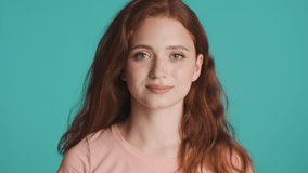 Pretty smiling redhead woman happily showing see you later gesture on camera over colorful background