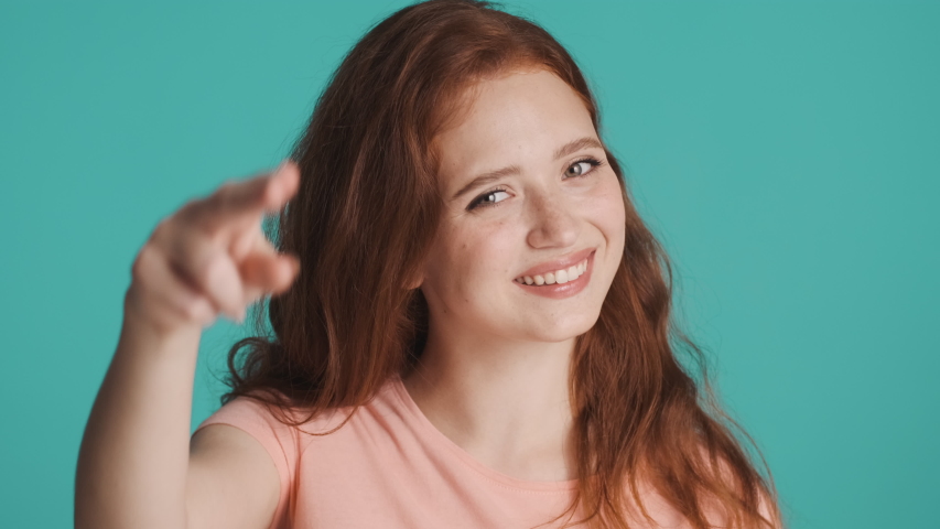 Pretty smiling redhead woman happily showing see you later gesture on camera over colorful background | Shutterstock HD Video #1056532169