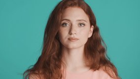 Attractive redhead woman surprisingly looking in camera over colorful background. Wow expression